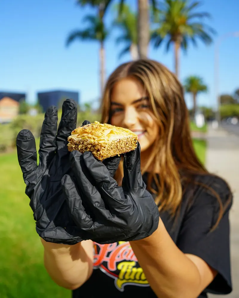 Holding up a piece of baklava in a gloved hand