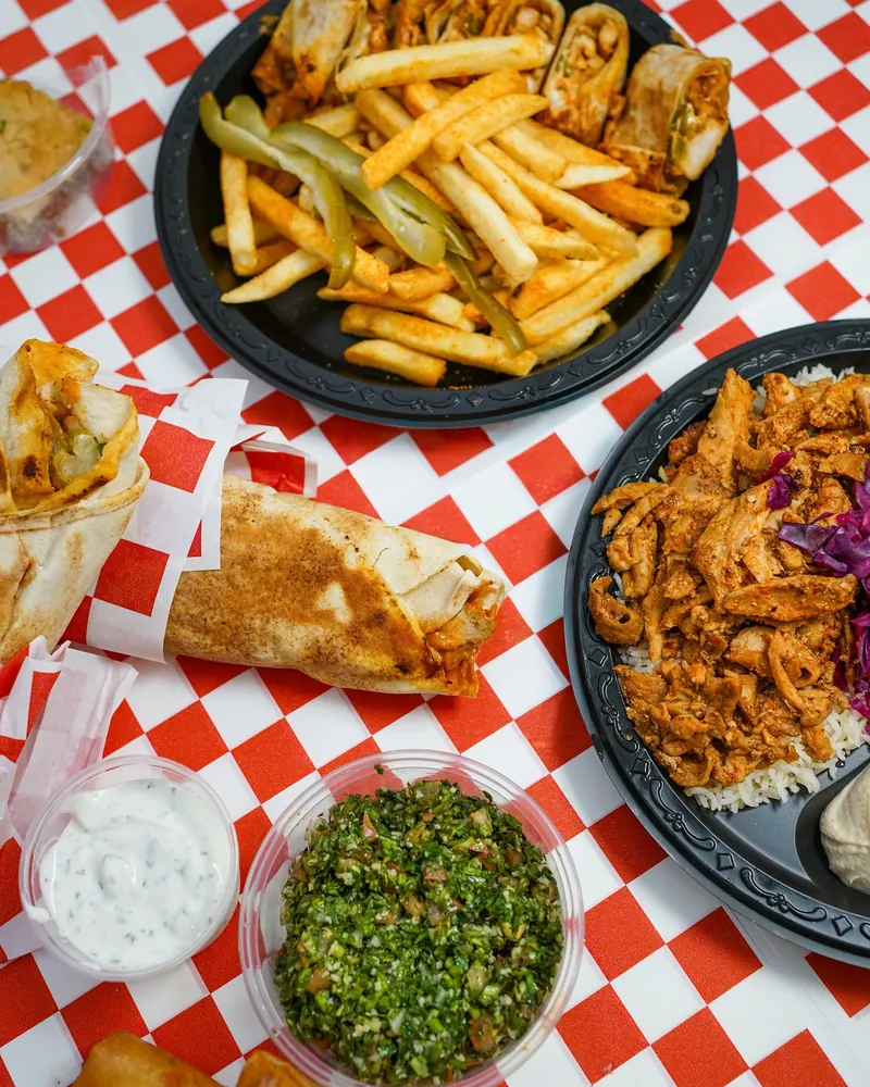 A table of shawarma plates, fries, tabbouleh and tzatziki