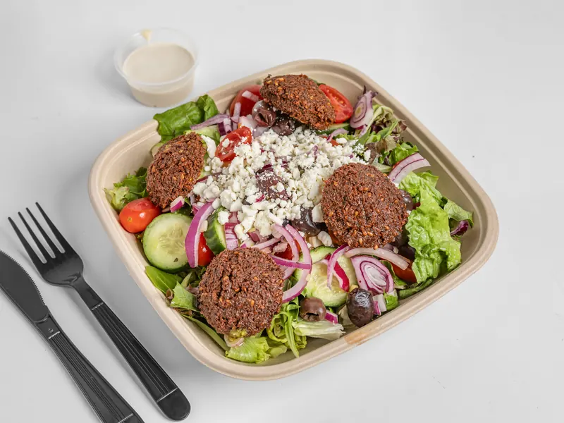 Protein bowl of Mediterranean salad topped with falafel and feta